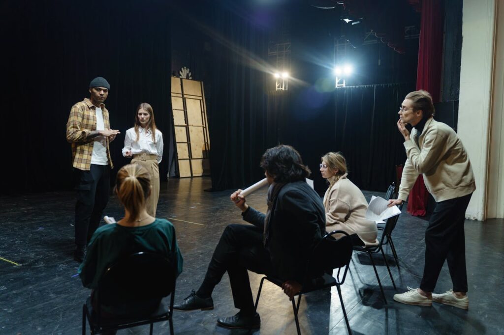 Actors rehearsing on stage with director's guidance in a theater for a live performance.